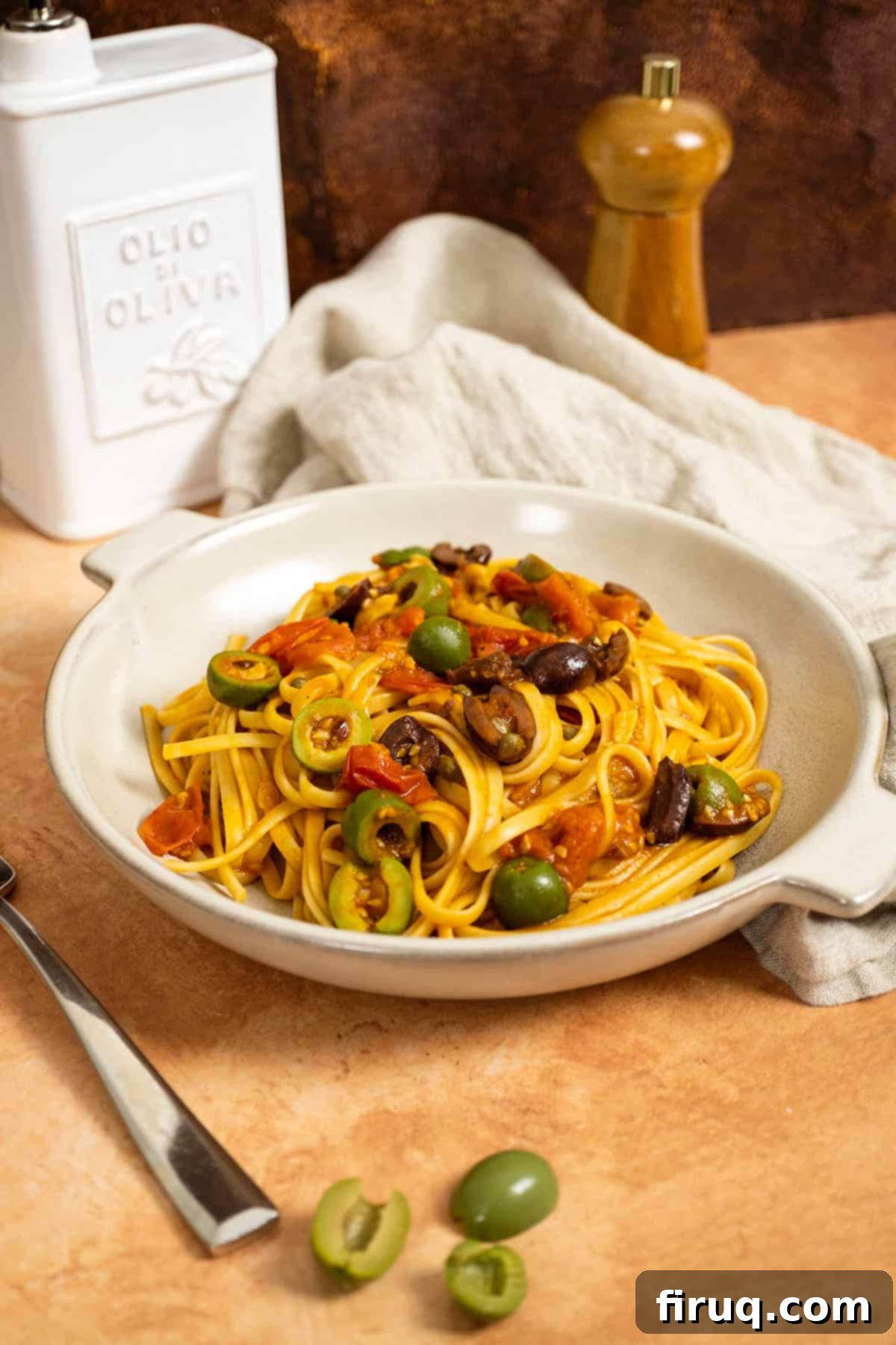Rustic Linguine Alla Puttanesca 2 Linguine puttanesca topped with olives and capers in a bowl. A vibrant dish with a rich red sauce, fresh herbs, and a scattering of dark olives and bright green capers, served in a white bowl.