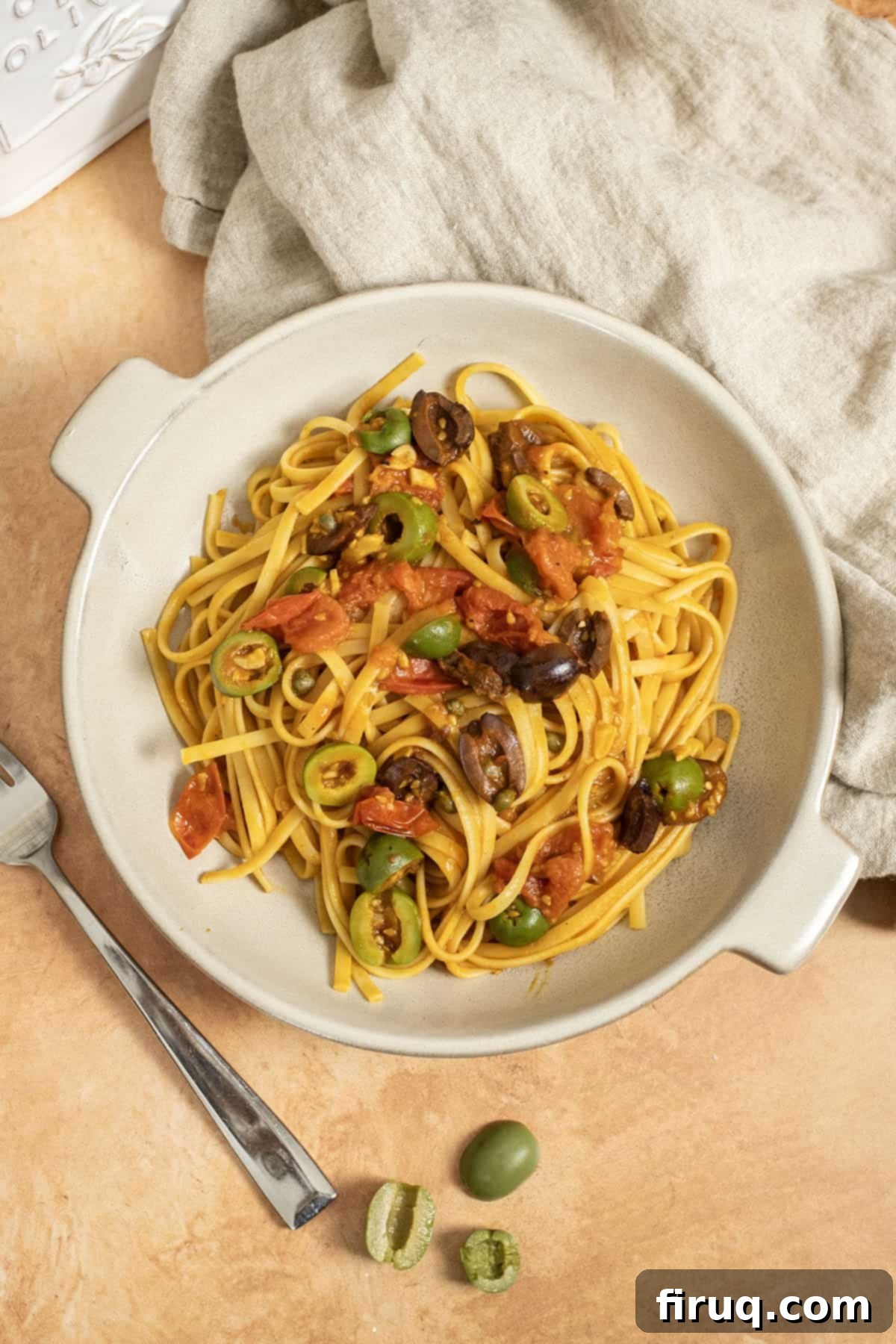 Rustic Linguine Alla Puttanesca 9 Linguine puttanesca topped with olives and capers in a bowl, ready to be enjoyed. The rich sauce and fresh ingredients are clearly visible, promising a delightful meal.