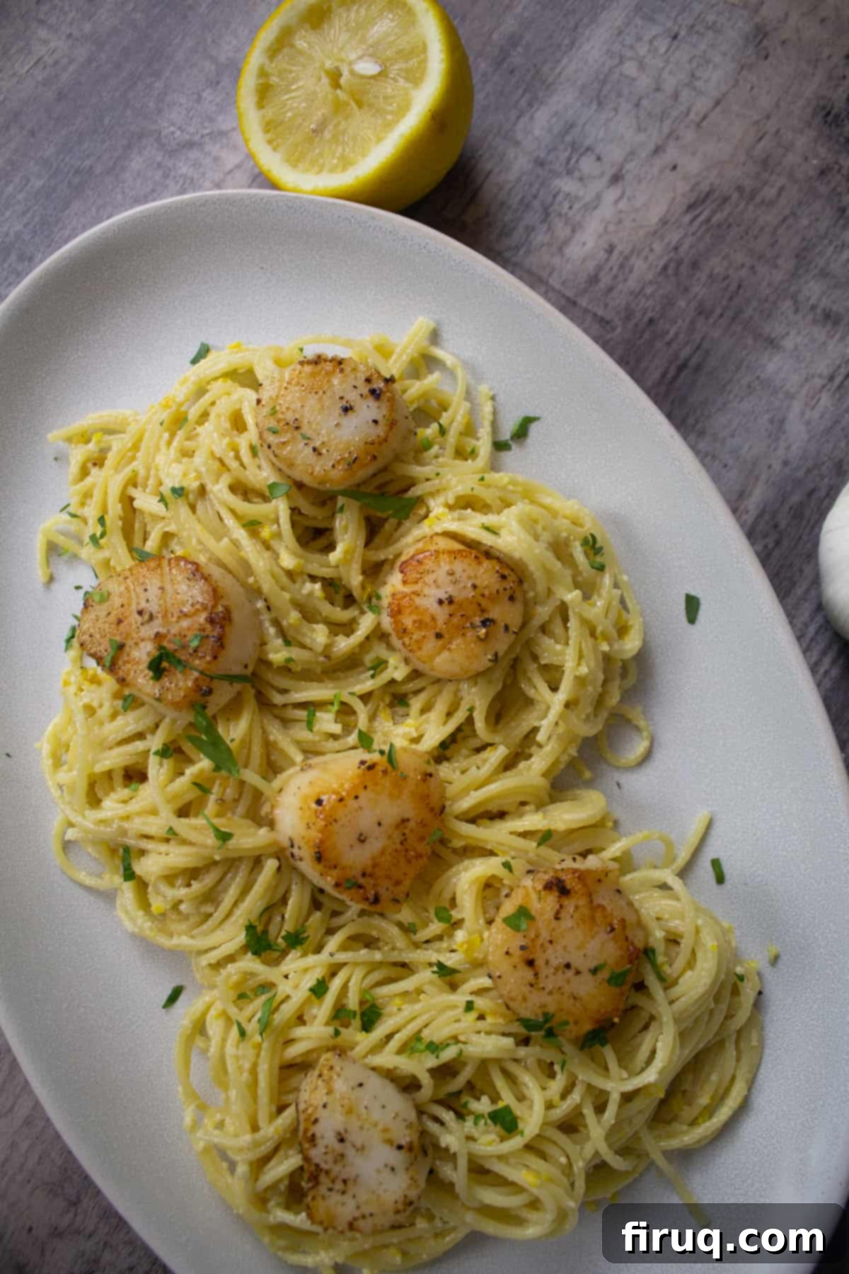 Bright Lemon Pesto Spaghetti with Pan-Seared Scallops 4 Close-up of lemon pesto spaghetti with scallops, a lemon half for garnish, emphasizing freshness