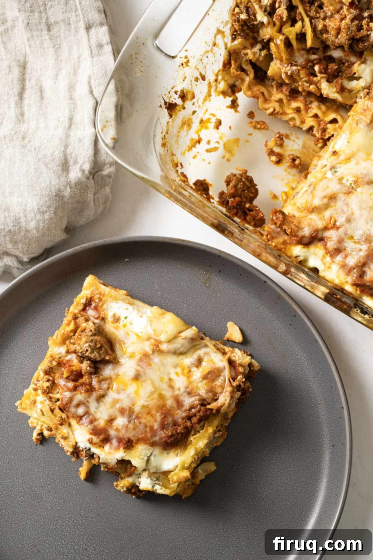 The Ultimate Homemade Italian Lasagna 14 A perfectly portioned square of authentic Italian lasagna on a white plate, with a large baking dish filled with more golden-brown lasagna in the background, ready to be served, inviting diners to enjoy a hearty Italian meal.