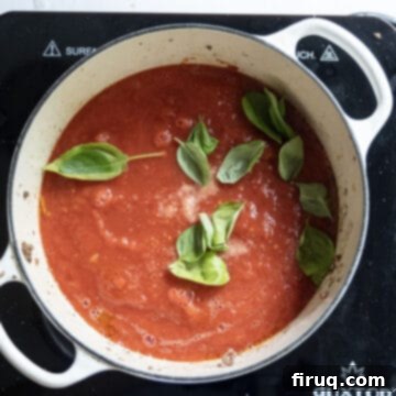 The Ultimate Homemade Italian Lasagna 8 A vibrant red tomato sauce simmering gently in a Dutch oven, garnished with fresh green basil leaves, creating a classic Italian aroma.