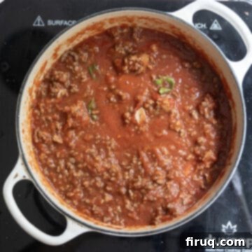 The Ultimate Homemade Italian Lasagna 9 Cooked ground meat added back to the simmering tomato sauce in a Dutch oven, creating a rich and hearty ragù for the lasagna.