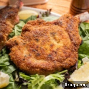 Golden Crispy Pork Milanese 10 Pork chop milanese over a greens salad and a wedge of lemon on the side.