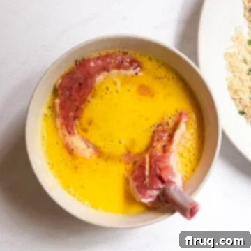 Golden Crispy Pork Milanese 5 Pork chop dipped in a bowl of whisked egg.