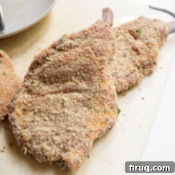 Golden Crispy Pork Milanese 6 Pork chops dredged in bread crumbs on a cutting board, ready for frying.