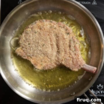 Golden Crispy Pork Milanese 7 Pork chop frying in olive oil in a pan.