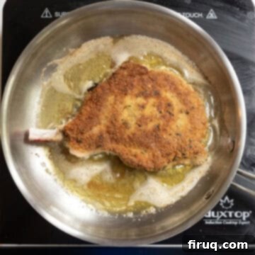 Golden Crispy Pork Milanese 8 Pork chop flipped over in frying pan with golden brown coating, showing its crispy texture.