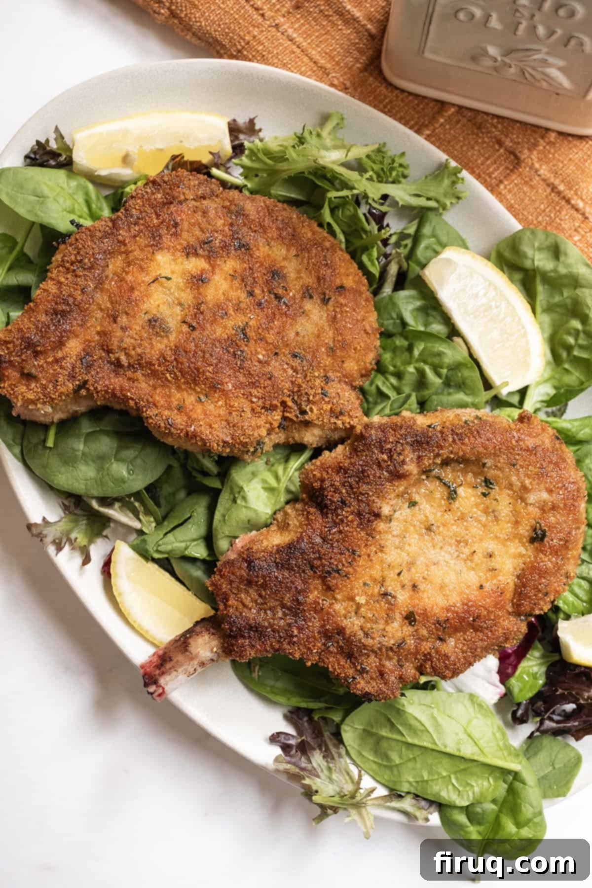 Golden Crispy Pork Milanese 9 Pork chop milanese over a greens salad and a wedge of lemon on the side.
