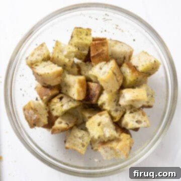 Crispy Homemade Parmesan Croutons 5 A bowl of chopped bread, thoroughly tossed with olive oil, garlic powder, Italian seasoning, and salt.