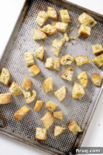 Crispy Homemade Parmesan Croutons 6 Seasoned bread cubes spread evenly in a single layer on a baking sheet.