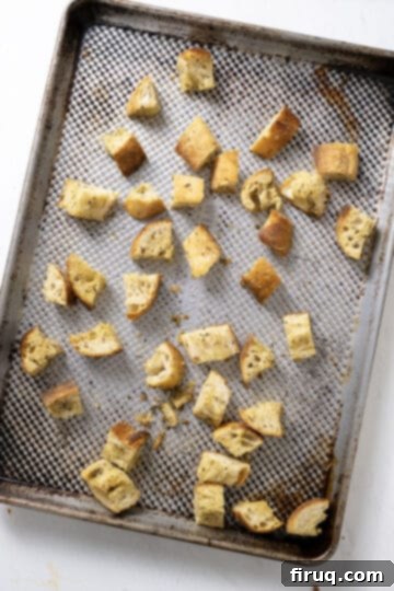 Crispy Homemade Parmesan Croutons 7 Freshly baked, golden-brown croutons cooling on a baking sheet.