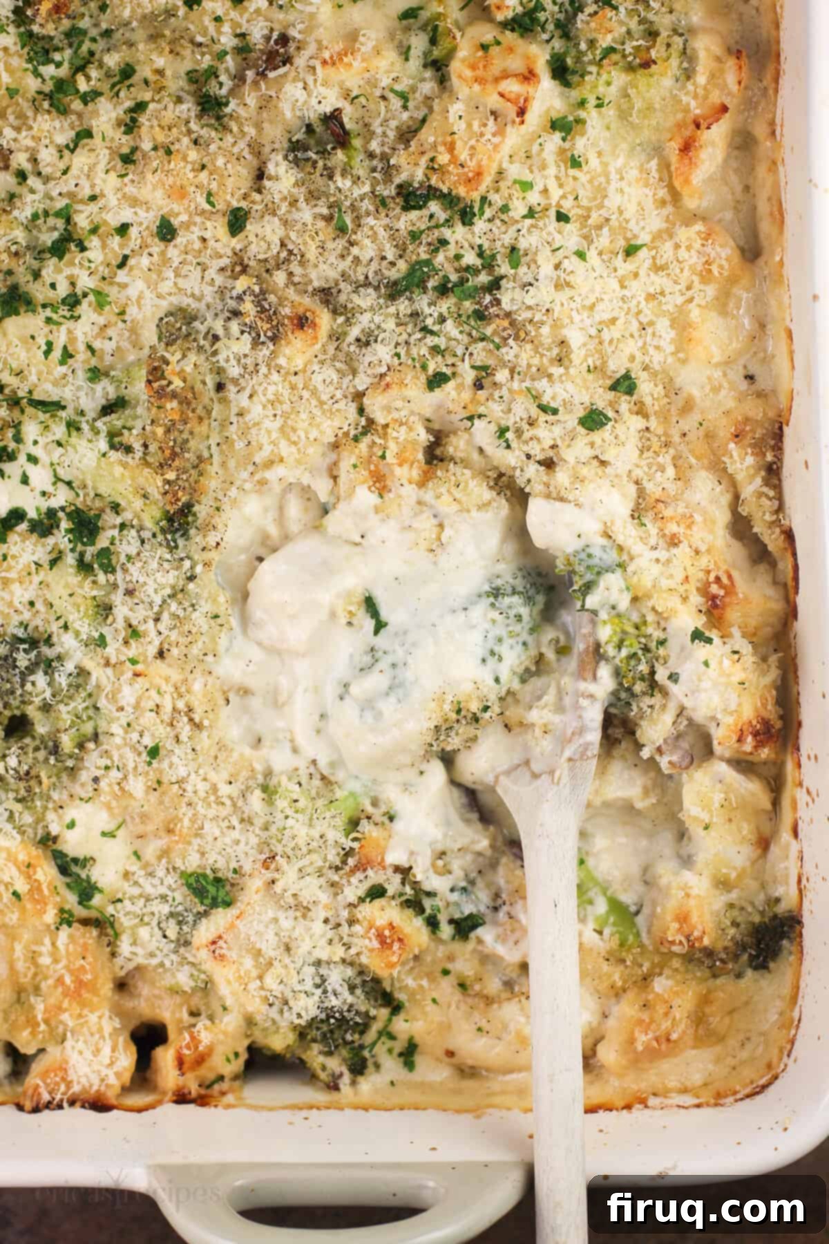 Creamy Chicken Broccoli Bake 8 A top-down view of a prepared Chicken Divan casserole dish, golden and bubbly, with a wooden spoon nestled in for serving.