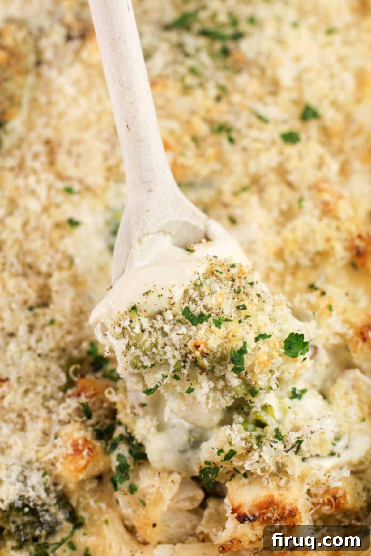Creamy Chicken Broccoli Bake 9 A serving spoon scoops into the cooked Chicken Divan, showcasing the layers of chicken, broccoli, and creamy sauce.