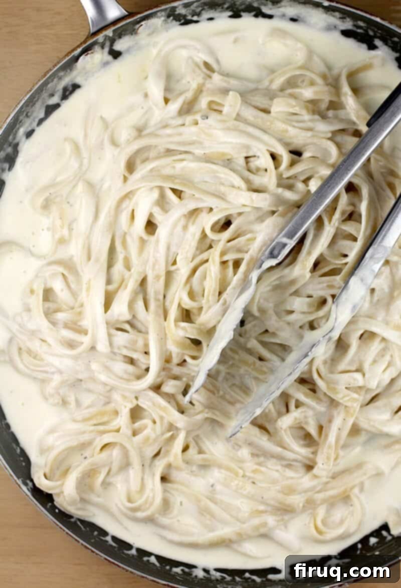Fettuccine Alfredo 11 noodles added to the alfredo sauce with a pair of tongs