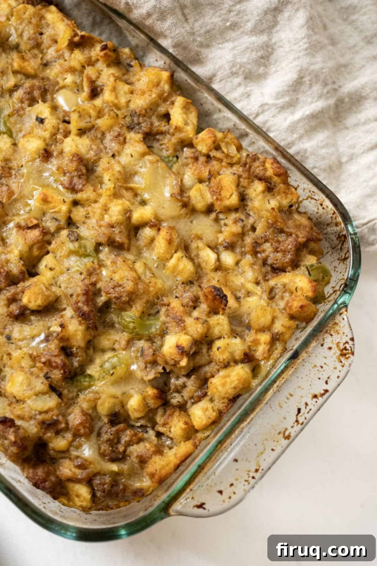 Robust Italian Sausage Thanksgiving Stuffing 2 Golden-brown Italian sausage stuffing baked to perfection in a clear glass baking dish, ready to be served for Thanksgiving.