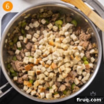 Robust Italian Sausage Thanksgiving Stuffing 7 Cubed bread stuffing being added to the browned Italian sausage and sautéed vegetables in a large saucepan.
