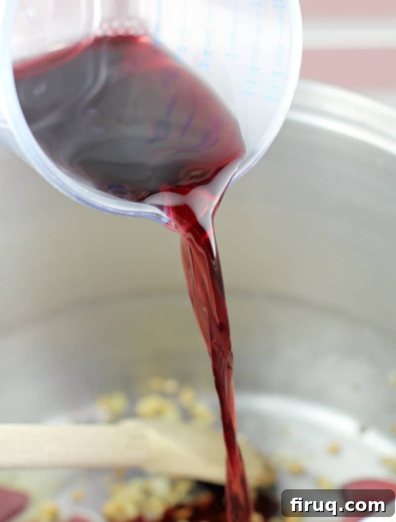 The Best Homemade Marinara 5 Clear plastic measuring cup pouring red wine into the pot