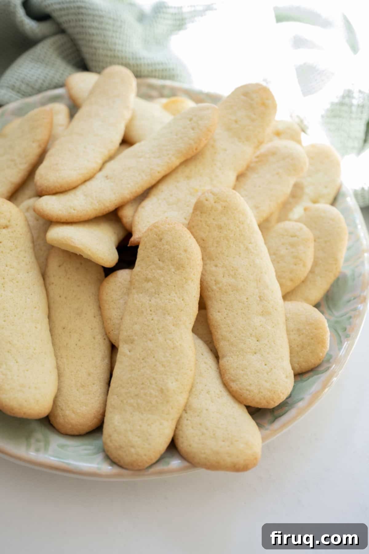 Homemade Ladyfingers for Perfect Tiramisu 2 Freshly baked homemade ladyfingers on a white plate, showcasing their light, golden appearance, ideal for Tiramisu.