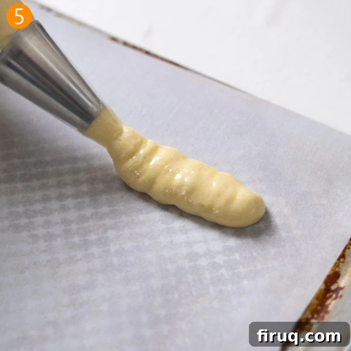 Homemade Ladyfingers for Perfect Tiramisu 8 Ladyfinger batter being precisely piped into uniform 4-inch finger shapes onto parchment paper on a baking sheet.