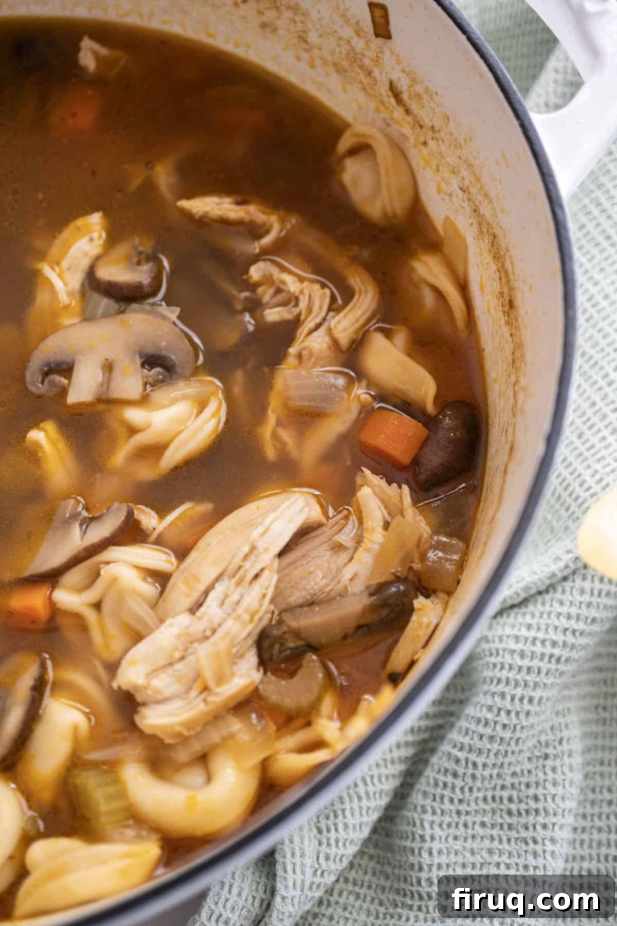 Creamy Chicken Tortellini Bliss 11 A large pot of rich chicken tortellini soup, brimming with shredded chicken, mushrooms, and vegetables.