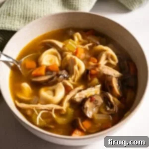 Creamy Chicken Tortellini Bliss 13 A delicious bowl of Chicken Tortellini Soup, garnished with fresh herbs, ready to be served.