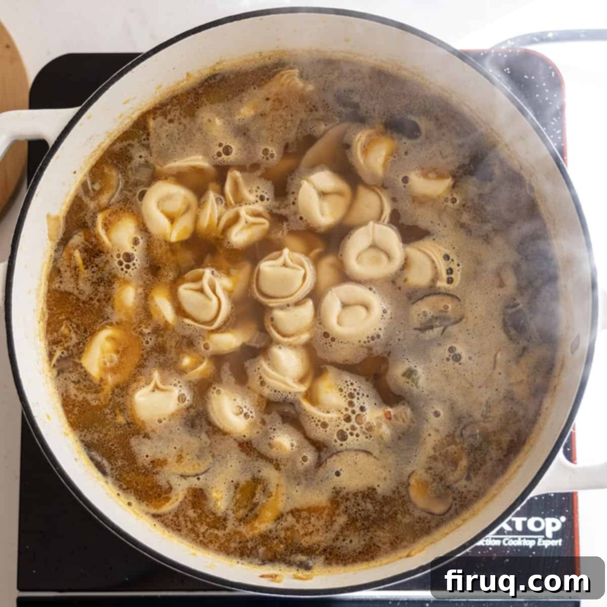 Creamy Chicken Tortellini Bliss 10 A large pot of chicken tortellini soup simmering, with tortellini floating among shredded chicken and vegetables.