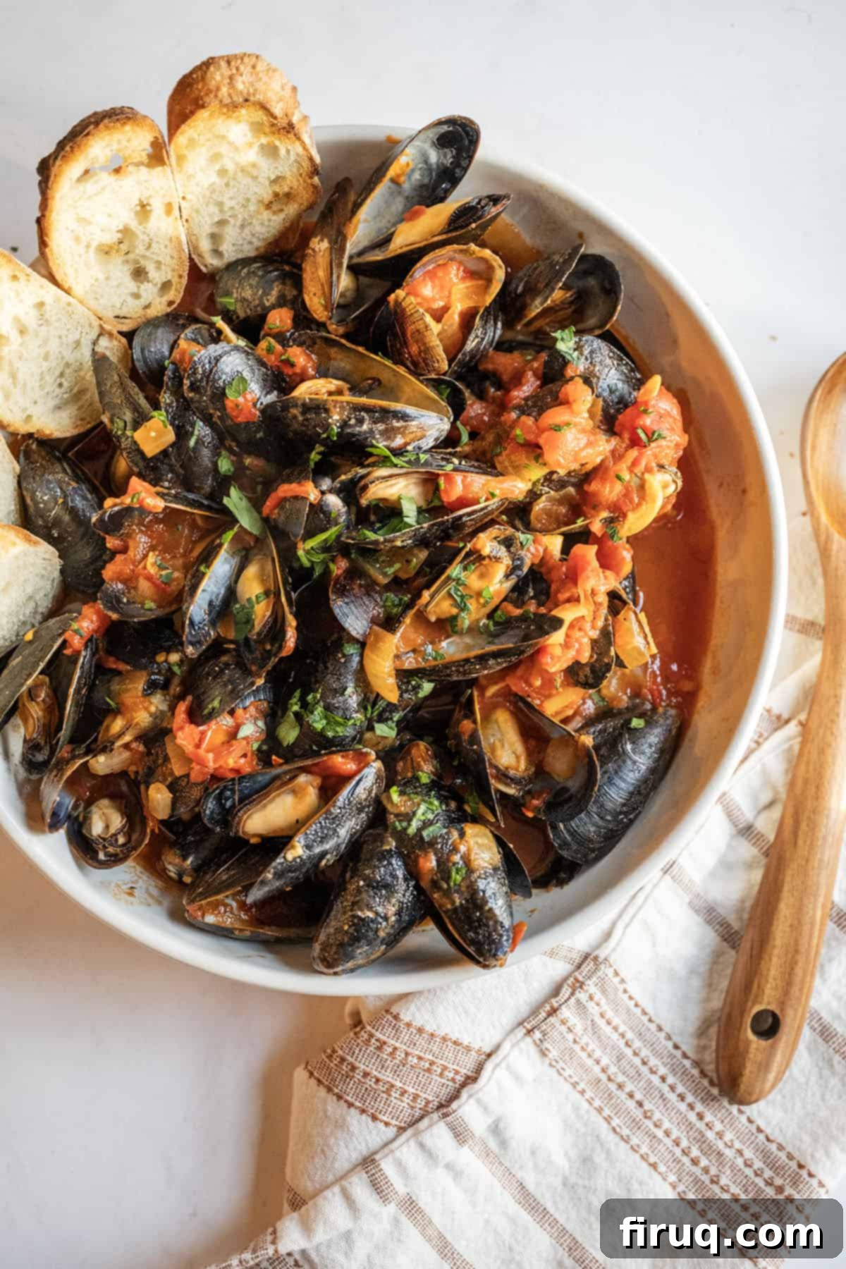 Devilishly Delicious Mussels 11 A large rustic bowl overflowing with Mussels Fra Diavolo, glistening with spicy red sauce and adorned with fresh parsley, presented beautifully on a wooden surface with crostini nearby.