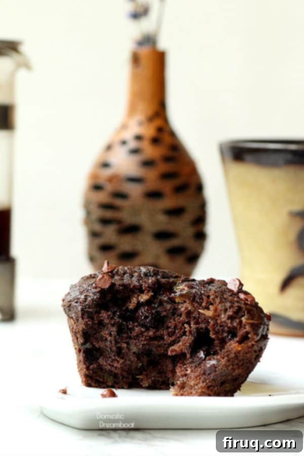 A cross-section of a moist double chocolate zucchini muffin Double chocolate zucchini muffin broken in half with flower vase and coffee cup