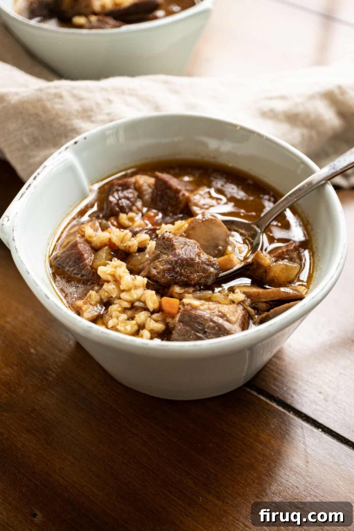 Hearty Beef Barley and Mushroom Soup 10 A serving of hearty beef and barley soup with mushrooms in a rustic bowl, garnished with fresh herbs.