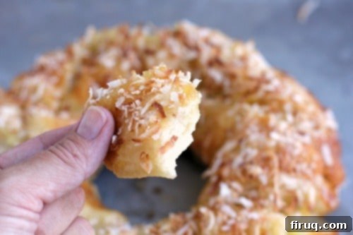 Tropical Pina Colada Pull-Apart Bread 3 Fingers pulling apart a warm, sticky piece of Pina Colada Monkey Bread, showcasing its delightful texture.