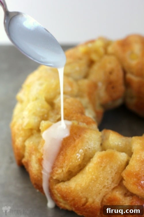 Tropical Pina Colada Pull-Apart Bread 6 A delicious Pina Colada Monkey Bread freshly baked with glaze being drizzled over it, ready for serving.