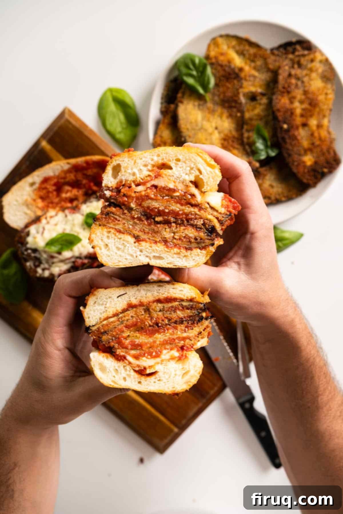 Eggplant Parmesan Sandwich 12 Holding an eggplant parm sandwich cut in half.