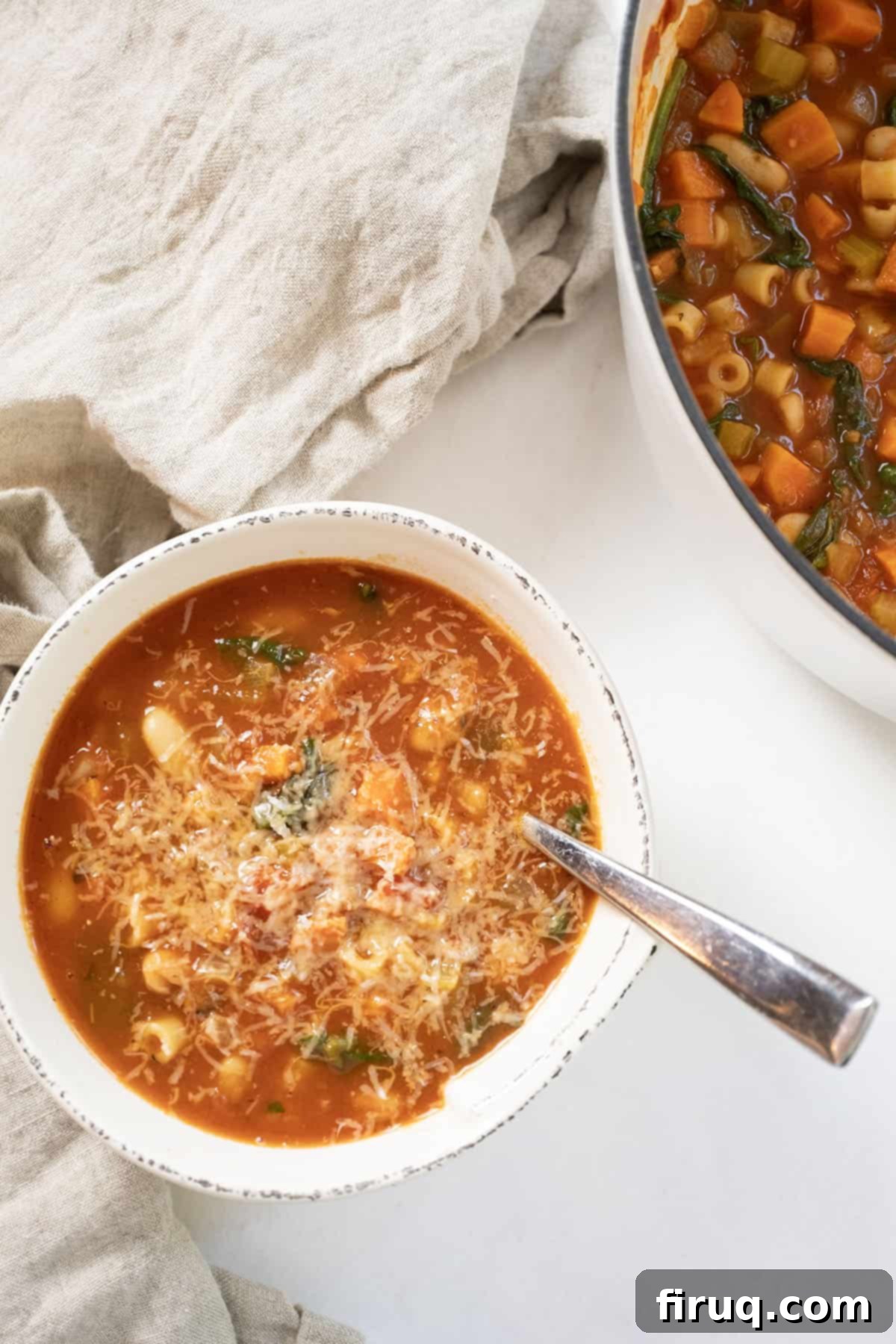 Hearty Italian Pasta and Bean Soup 12 Pasta fagiolo topped with parmesan in a bowl next to the full pot of soup.