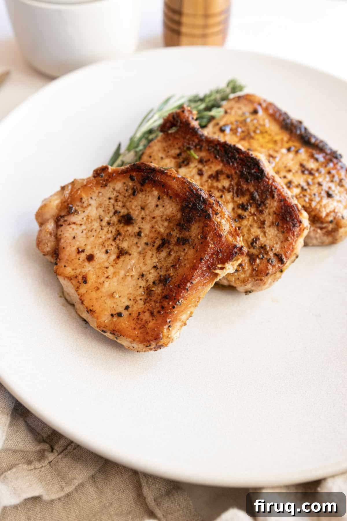 Crispy, Juicy Cast Iron Boneless Pork Chops 9 Boneless pork chops cooked on a plate with rosemary and thyme