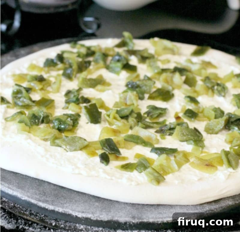 Popper's Paradise Pie 5 pizza dough rolled out on a stone, topped with sauce and peppers