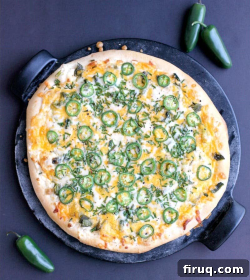Popper's Paradise Pie 9 top down view of the finished pizza on the pizza stone with a black background. a couple jalapenos are scattered around