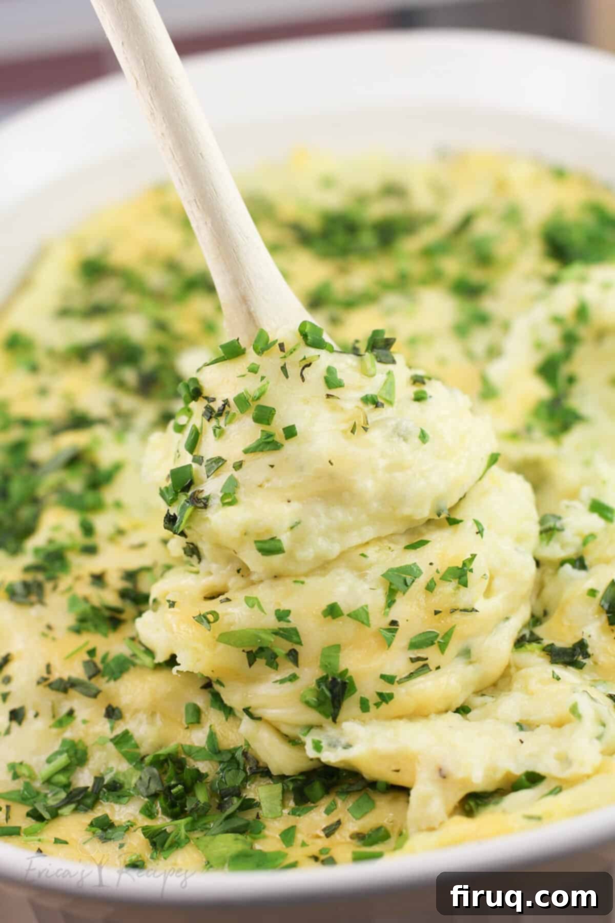 Garlicky Gruyere and Gouda Mashed Potatoes 12 wood spoon lifting up cheesy mashed potatoes from bake dish