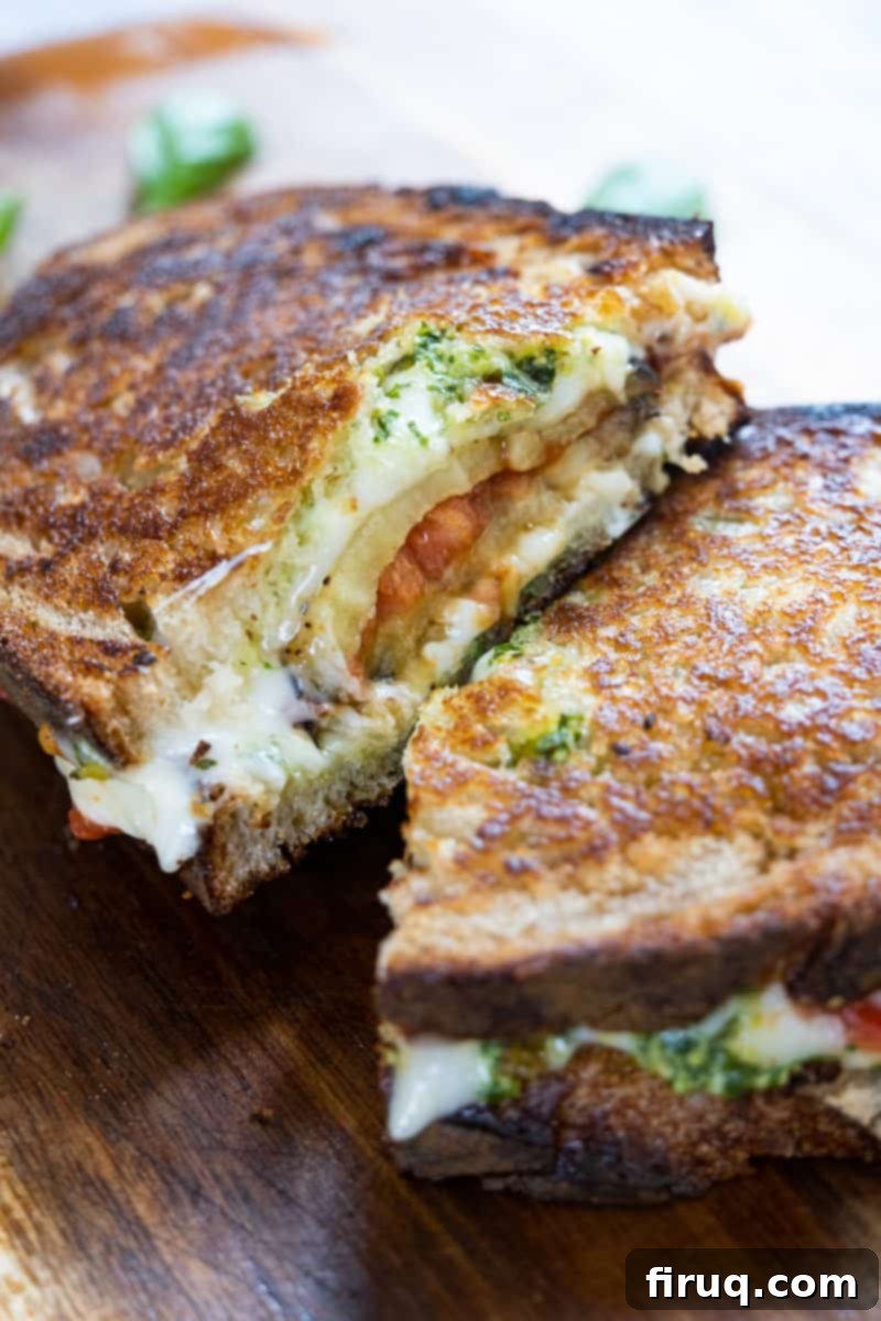 Ultimate Caprese Eggplant Melt 2 Delicious Eggplant Caprese Grilled Cheese sandwich, golden brown and cut in half, showcasing layers of grilled eggplant, roasted tomatoes, pesto, and melted cheese.