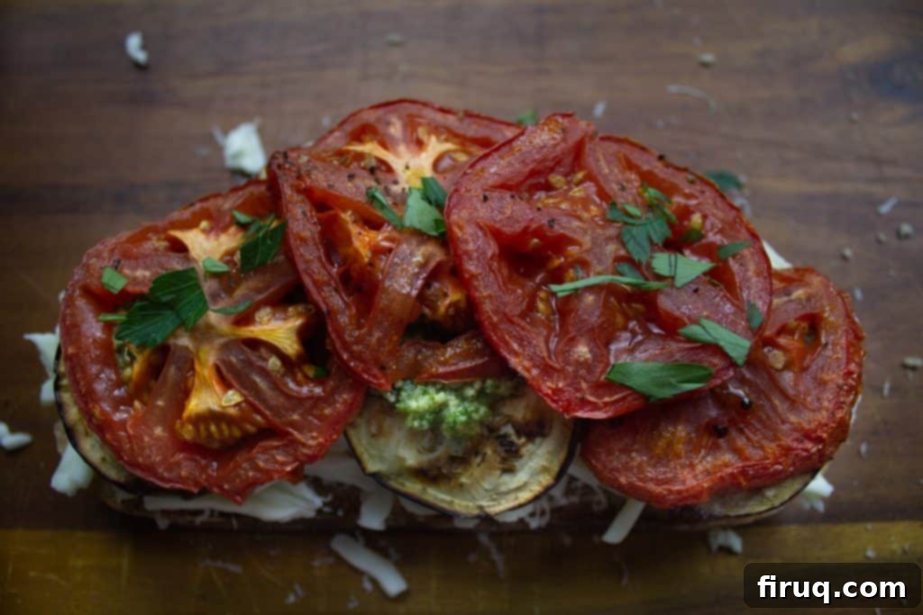 Ultimate Caprese Eggplant Melt 6 An open Eggplant Caprese Grilled Cheese, showing the layers of grilled eggplant, roasted tomatoes, pesto, basil, and cheese before the top slice of bread is added for frying.