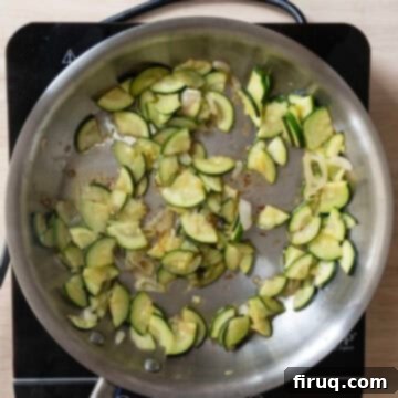 Creamy Zucchini Risotto 5 Sliced zucchini sauteing with translucent shallots in a saucepan.