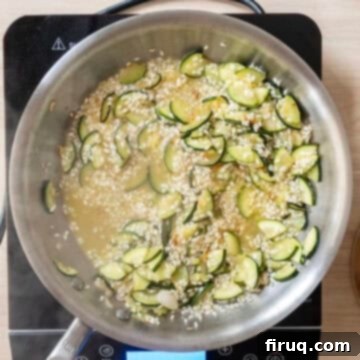 Creamy Zucchini Risotto 7 White wine simmering with arborio rice in a saucepan, deglazing the pan.