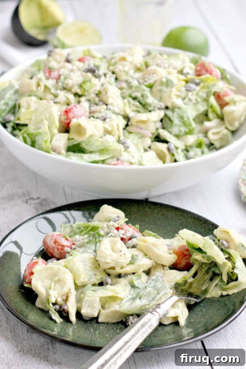 Creamy Avocado Tortellini Salad 3 Close-up of a colorful tortellini salad on a green plate, with a fork digging in to show the texture and ingredients of the southwest-inspired dish