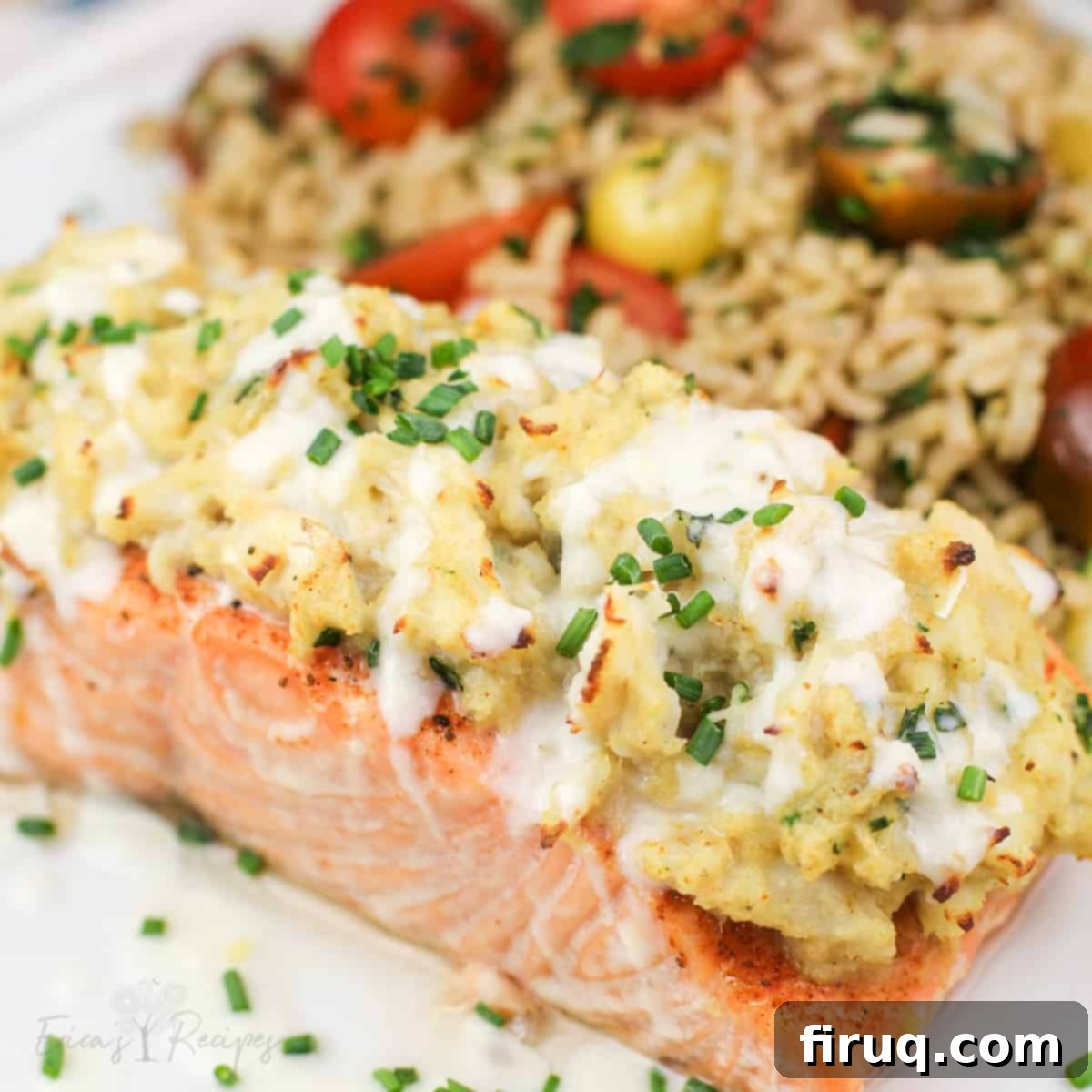 Gourmet Crab Stuffed Salmon 3 crab stuffed salmon on white plate topped with chives and light lemon sauce. rice with cherry tomatoes in the background
