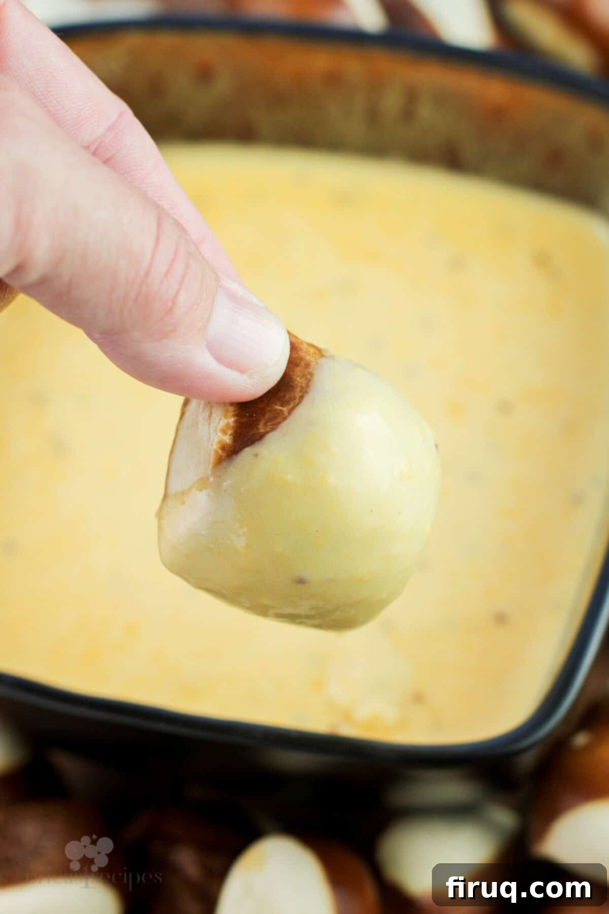 Traditional German Beer Cheese 6 hand holding pretzel bread bite dipped in german cheese dip