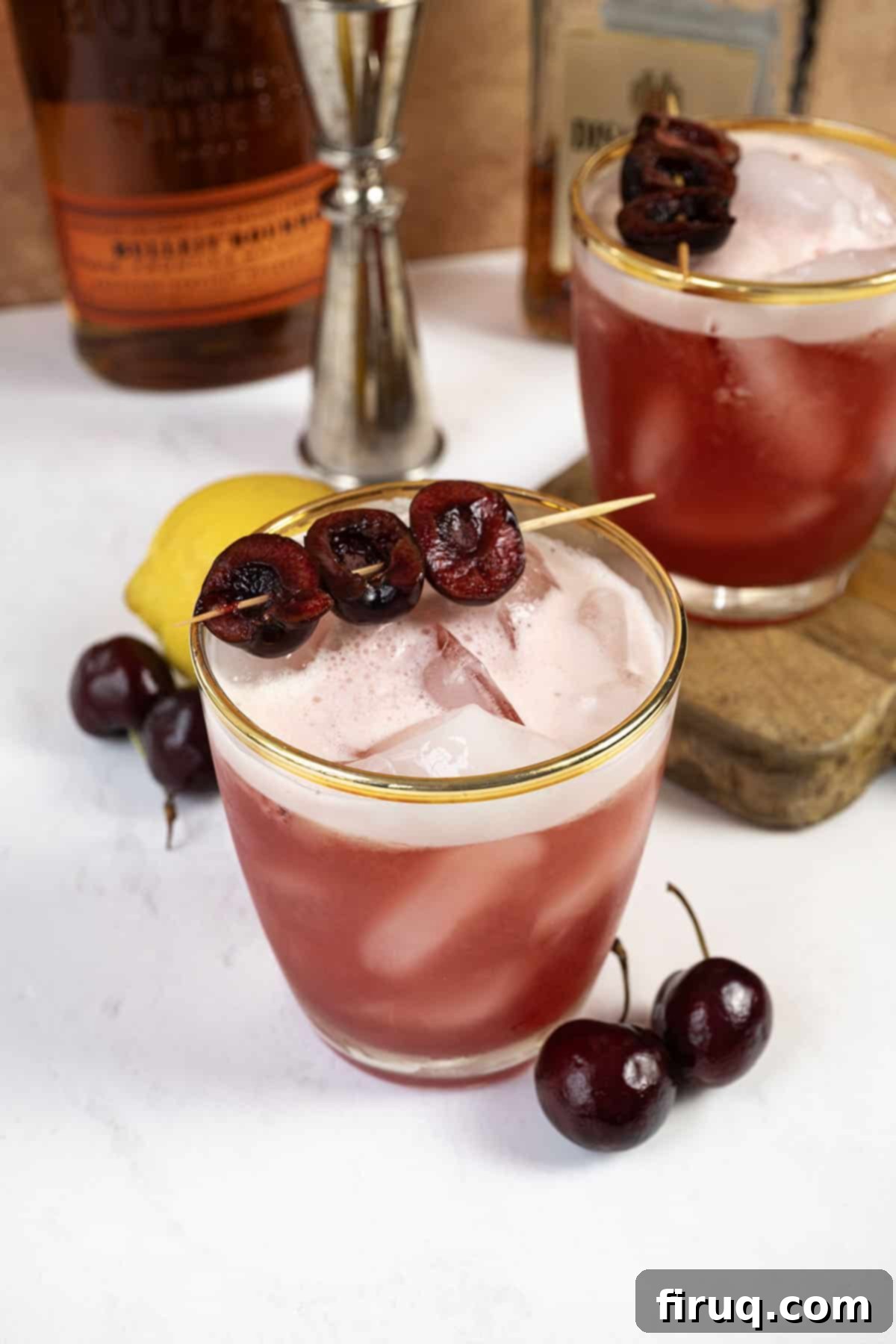 Crimson Amaretto Sour 2 A vibrant Cherry Amaretto Sour cocktail in a rock glass, garnished with fresh cherries on a toothpick and a frothy white top.