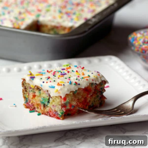 Effortless Funfetti Cake 2 Closeup photo of a finished easy sprinkle cake on a plate, topped with smooth frosting and colorful jimmies.