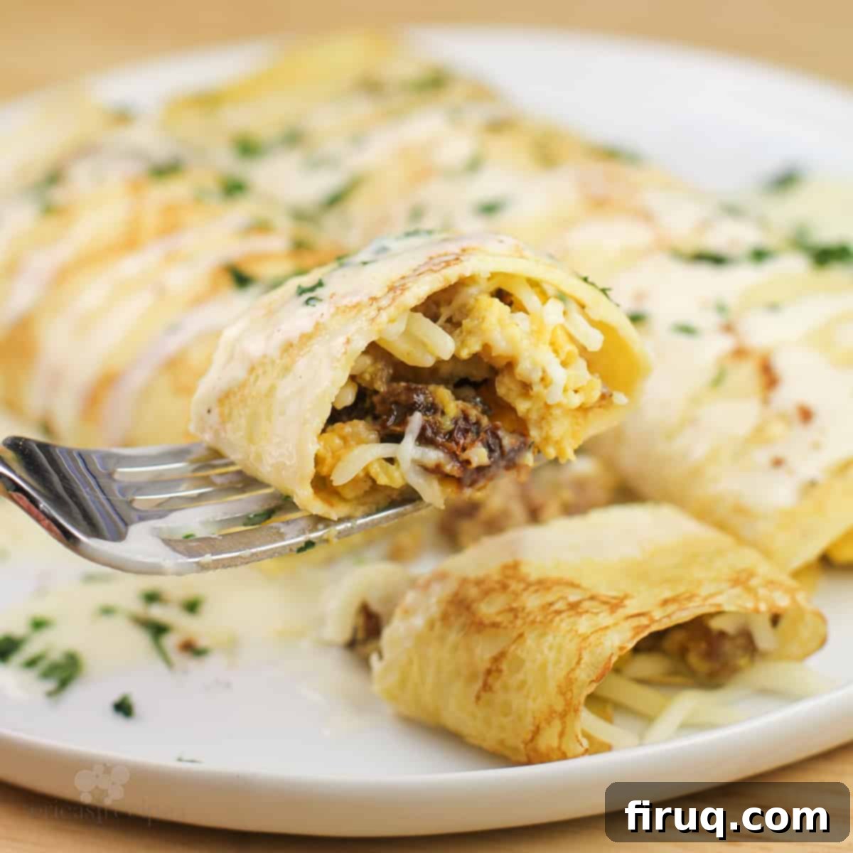 Sweet & Savory Sausage Crepes with Maple Béchamel 3 piece of prepared recipe on fork over white plate