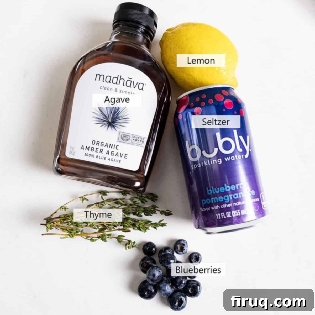 Blueberry Smash Mocktail 3 Carefully arranged ingredients for the blueberry mocktail including fresh blueberries, lemon, thyme, agave, and a bottle of seltzer.