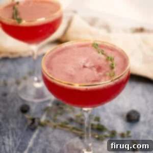 Blueberry Smash Mocktail 5 Two blueberry mocktails with a sprig of thyme garnish in elegant glasses, ready for enjoyment.
