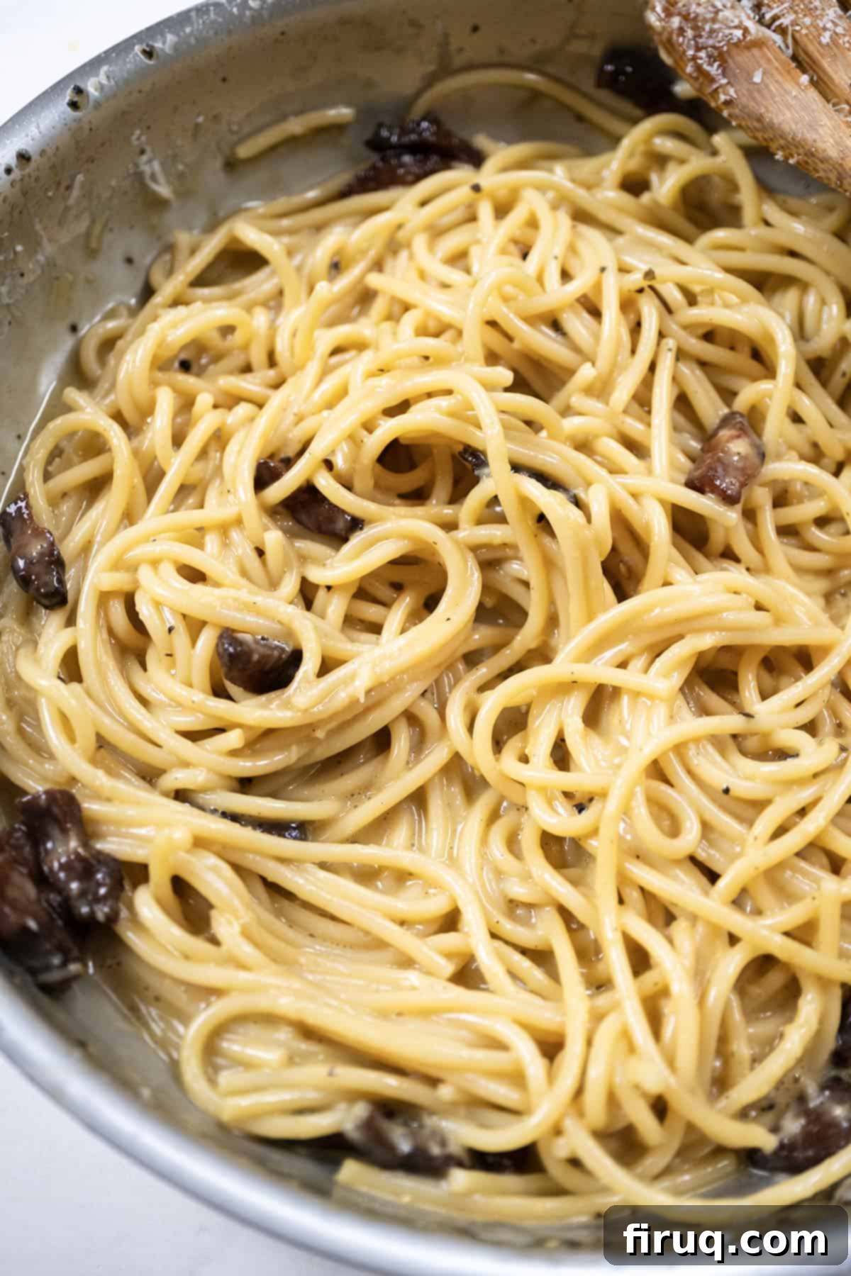 The Ultimate Carbonara Do's and Don'ts 11 Spaghetti Carbonara in a pan, showing the sauce transforming from liquidy to creamy as it's stirred.